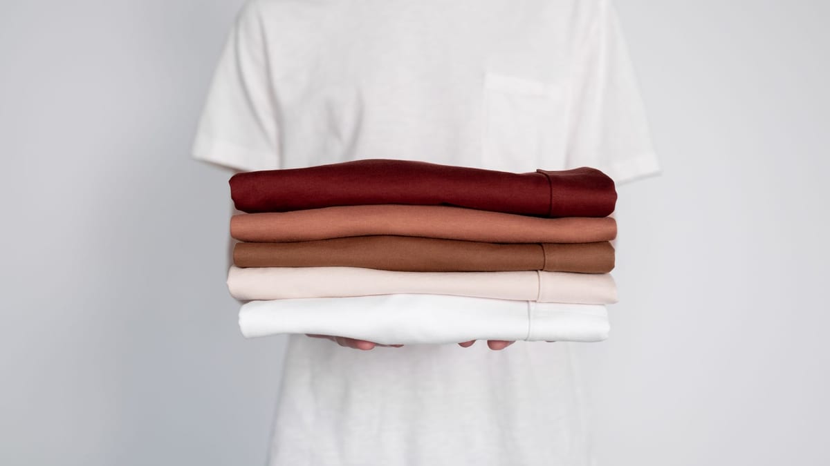 A stack of folded cotton t-shirts in five colours